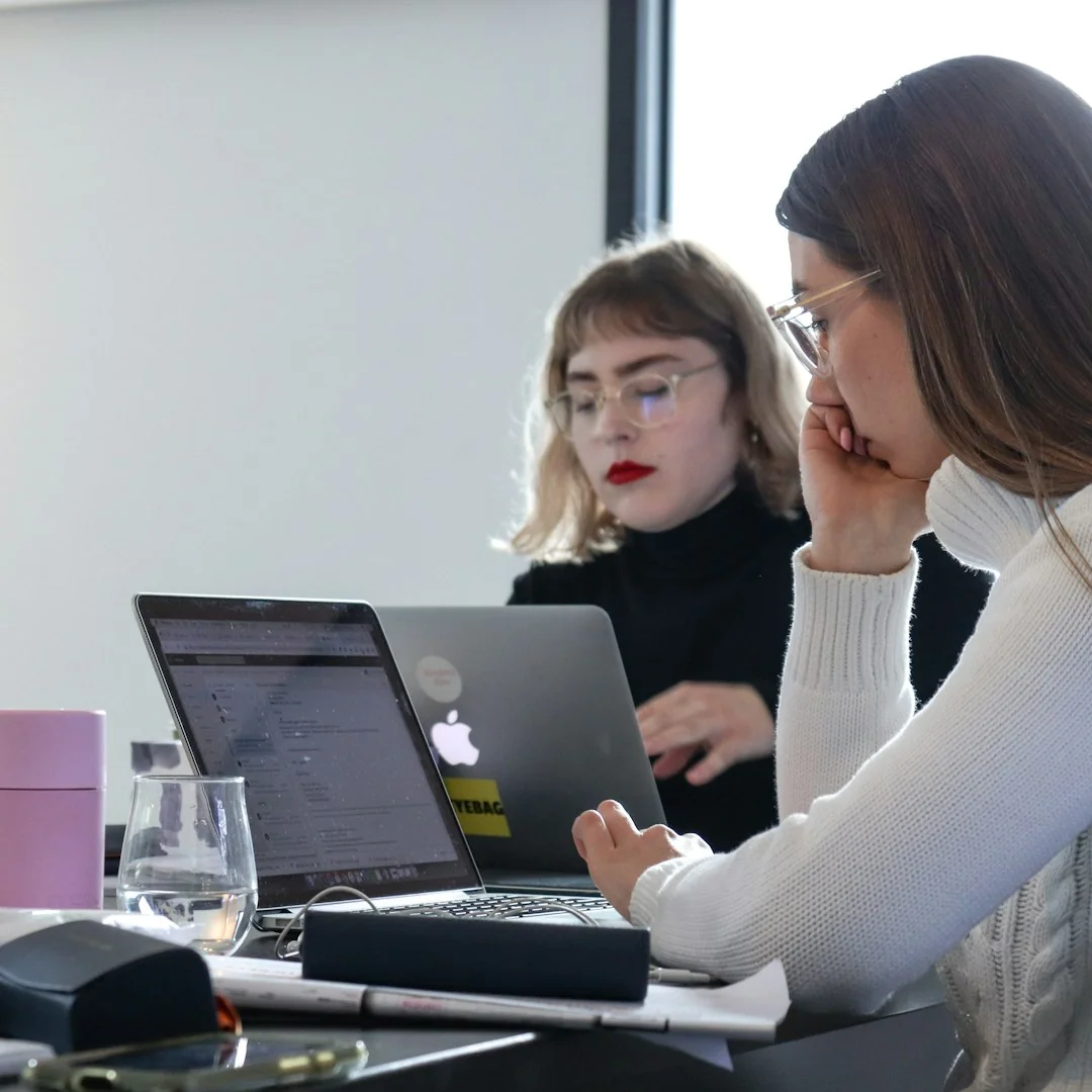 Diverse group of women working together in a modern office setting, fostering teamwork and creativity.